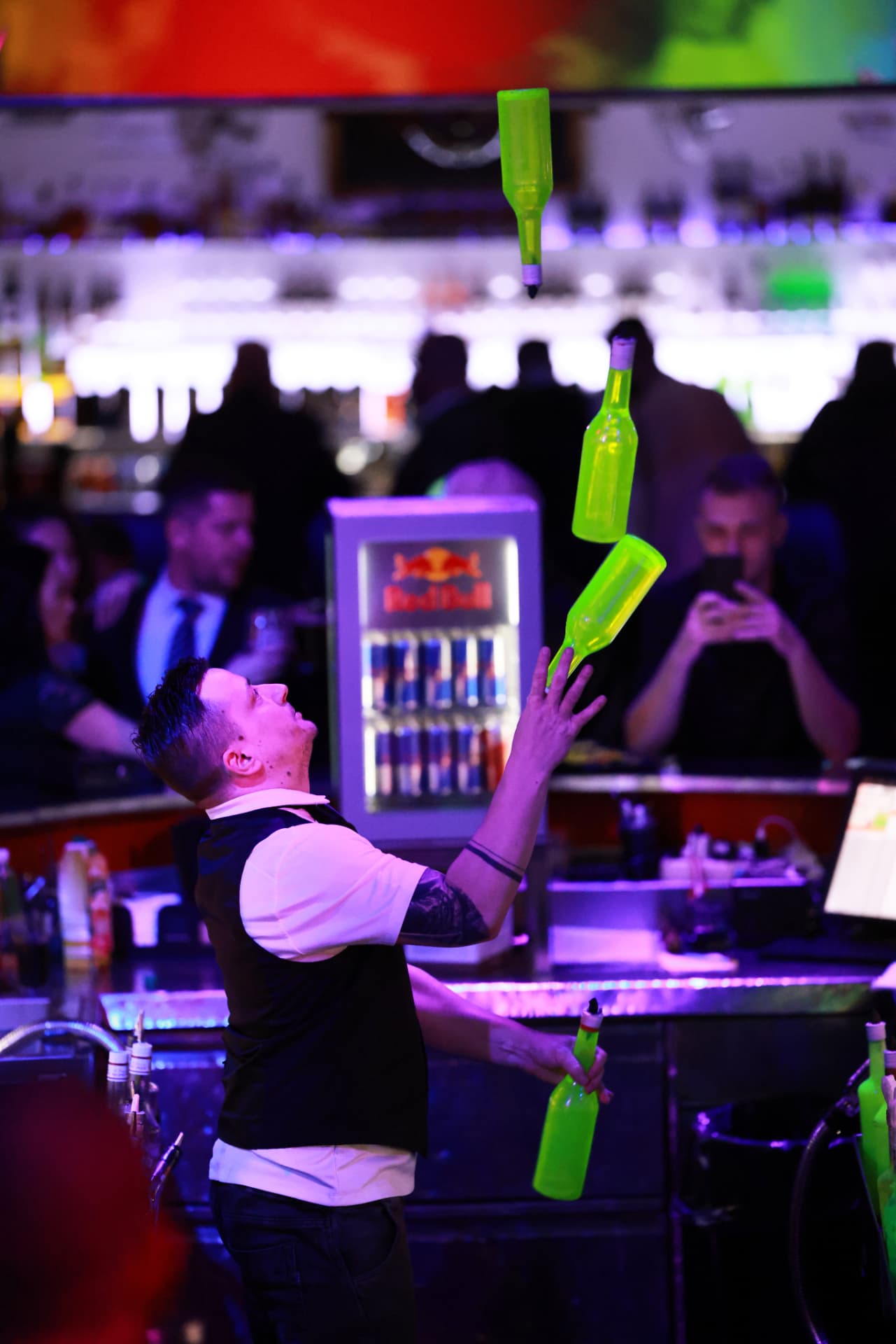 Barman při barmanské show s lahvemi ve vzduchu na 2. charitativním plese