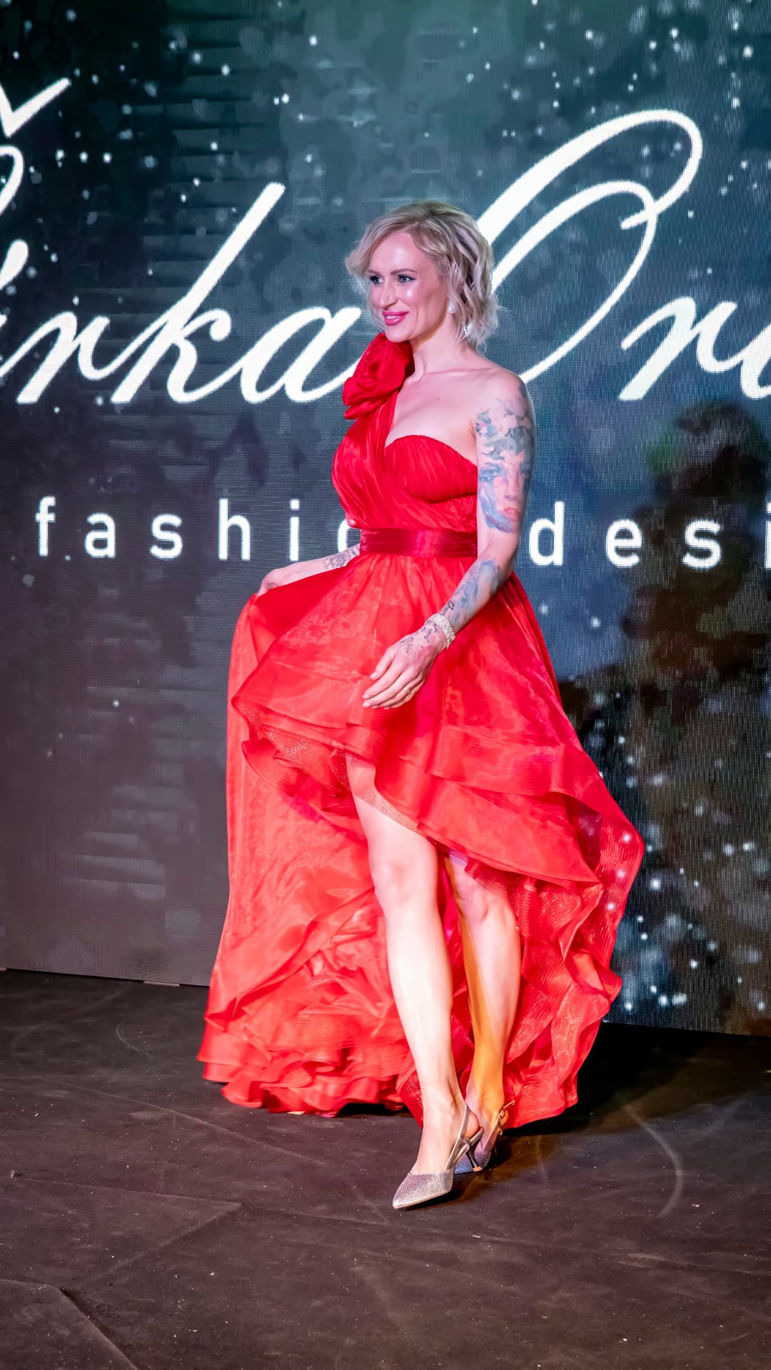 Modelka v červených šatech při módní přehlídce 3. plesu