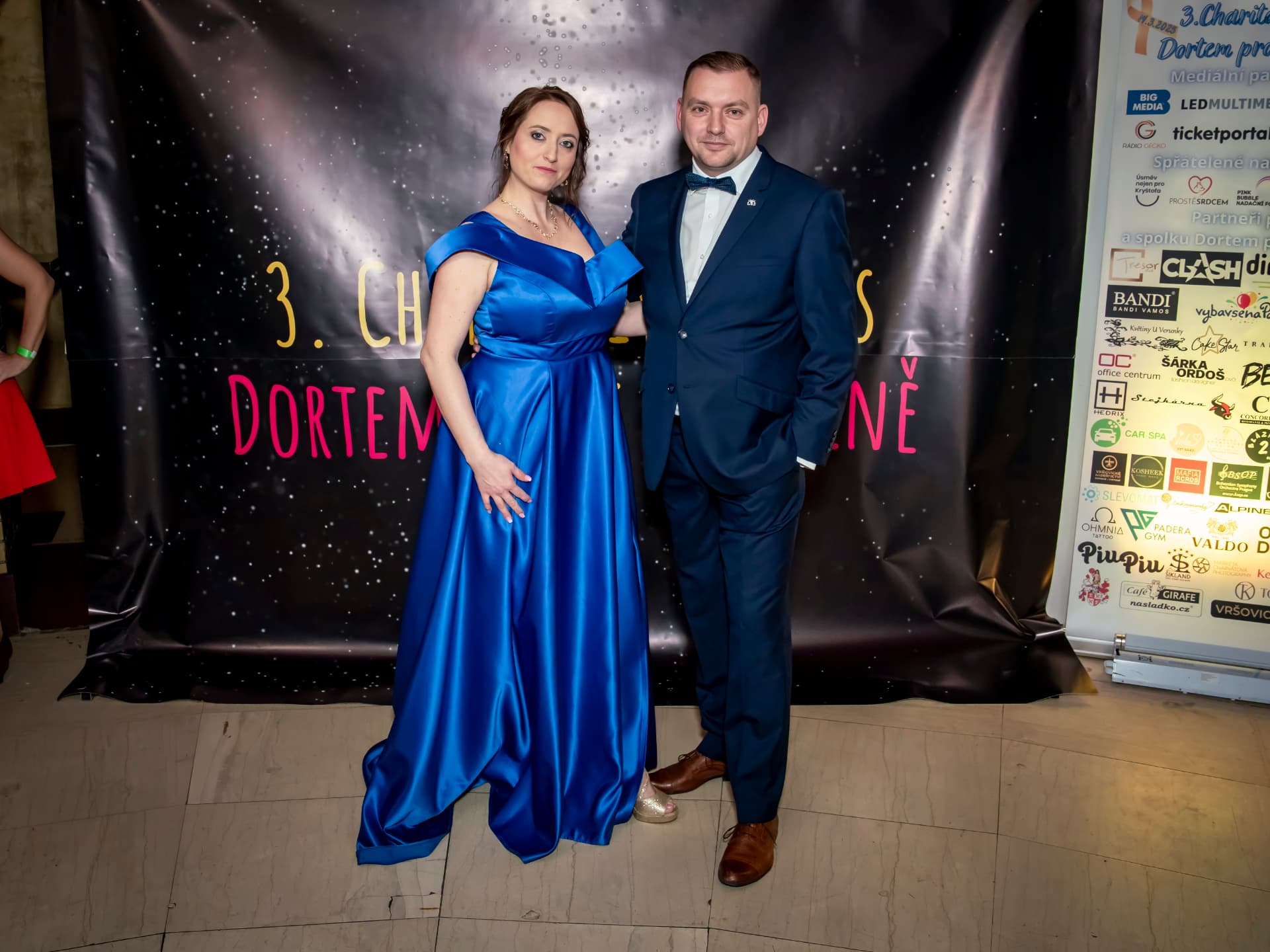 Hosté 3. charitativního plesu u fotografické stěny s logy partnerů