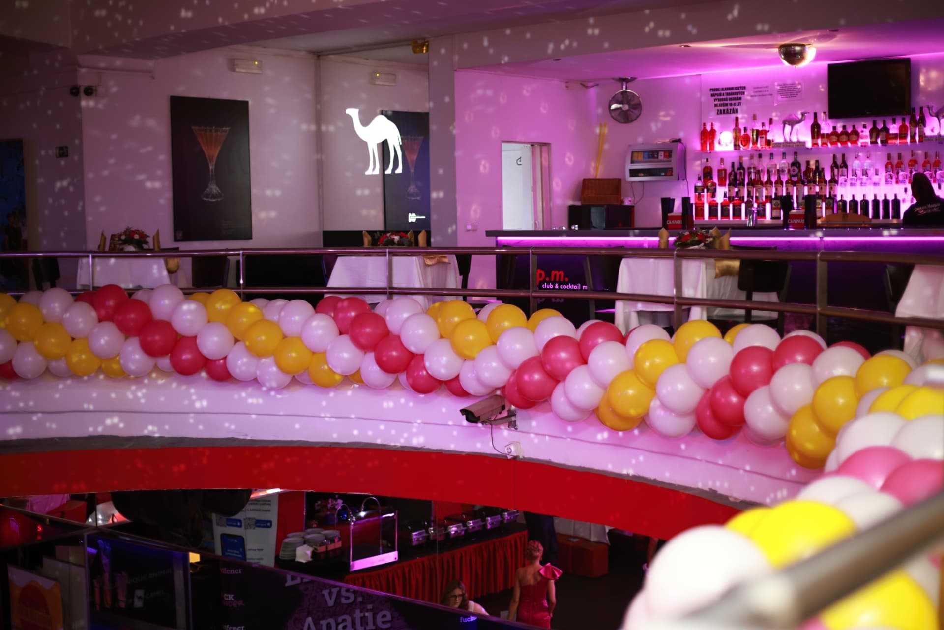 Pohled na bar klubu ze ochozu vyzdobeného balónky na 2. charitativním plese